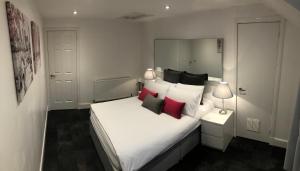 a bedroom with a large white bed with red pillows at L&H APARTMENTS in Inverness