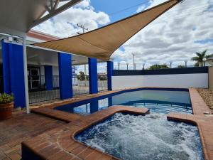 a swimming pool with an umbrella on a patio at Rockhampton Court Motor Inn in Rockhampton