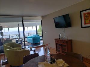 sala de estar con TV, mesa y sillas en Departamento Reñaca, en Viña del Mar