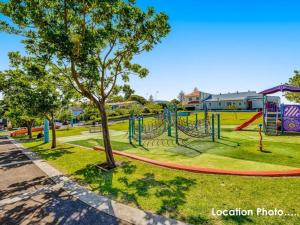 um parque infantil num parque com uma árvore em The View at Seascape em Gerringong