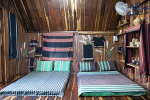 - 2 lits dans une chambre dotée de murs en bois dans l'établissement Khu Du Lịch Sinh Thái AkoEa, à Buôn Ma Thuột