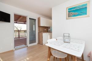 a kitchen and dining room with a white table and chairs at Mobile home Sea Bream in Pašman