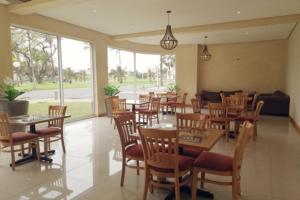 a restaurant with wooden tables and chairs and windows at Regal Inn North Beach in Durban