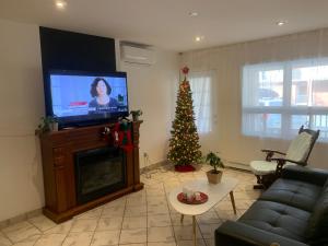 a living room with a christmas tree and a television at Hotel and Suites Les Laurentides in Saint-Sauveur-des-Monts
