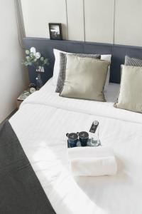 Una cama blanca con dos tazas y un teléfono celular. en B48 Hotel, en Bangkok
