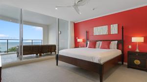 a bedroom with a red wall with a bed and a balcony at Oaks Hervey Bay Resort and Spa in Hervey Bay