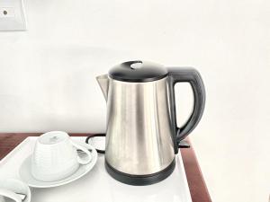 a stainless steel coffee pot sitting on a table with a plate at Sandy Residence Sihanoukville in Sihanoukville