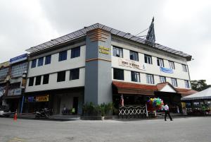 un gran edificio blanco con gente caminando delante de él en SRP Hotel Sdn Bhd en Batu Caves