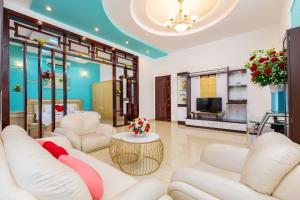 a living room with white furniture and a tv at Victory Villa - Sân Vườn - Hồ Bơi - Karaoke - Gần Biển Bãi Sau in Vung Tau