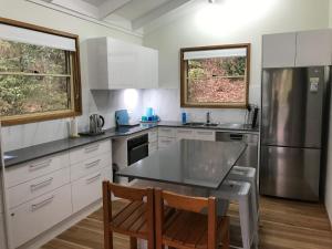 a kitchen with a stainless steel refrigerator and a table at Araluen in Smiths Lake