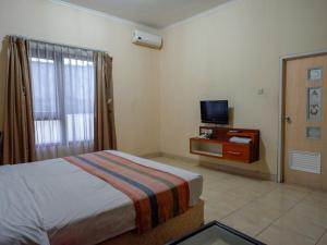 Habitación de hotel con cama y TV en Pineapple Mansion Solo Mitra RedDoorz near RS JIH Solo, en Solo