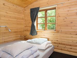 a bed in a wooden room with a window at Peaceful Holiday Home in Jutland with Sauna in Ebeltoft