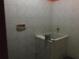 a white tiled bathroom with a sink and a toilet at Hotel SiCantik in Kaliurang