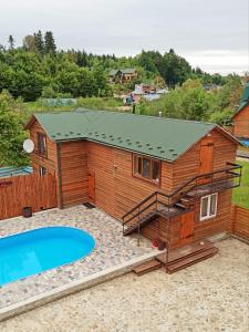 un gran edificio de madera con una piscina y una casa en Hirskyy Svitanok, en Migovo