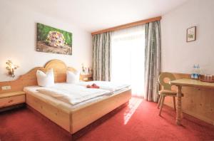 a bedroom with a bed and a desk and a window at Hotel Metzgerwirt in Kirchberg in Tirol