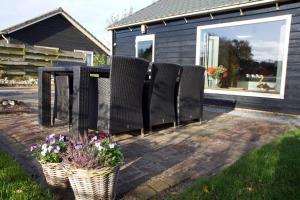 eine Terrasse mit Stühlen, einem Tisch und Blumen in der Unterkunft De Schaapskooi - Knus Veluws vakantiehuisje in Ede