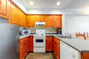uma cozinha com armários de madeira e um forno de fogão branco em Lake Placid Lodge em Whistler