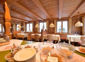 un restaurante con mesas y sillas blancas y ventanas en Gästehaus Roseneck, en Todtmoos