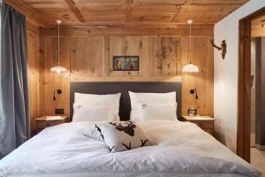 una camera da letto con un grande letto bianco e pareti in legno di Sotciastel Antico Chalet a Badia