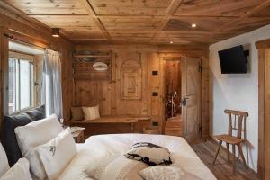 1 dormitorio con cama blanca y techo de madera en Sotciastel Antico Chalet, en Badia