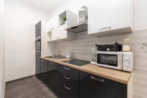 eine Küche mit einer Spüle und einer Mikrowelle in der Unterkunft Apartment LUX HOME in Rijeka