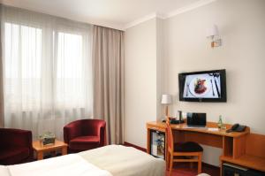 a hotel room with a bed and a desk with a computer at Hotel Filmar in Toruń