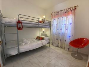 1 dormitorio con 2 literas y silla roja en Casa Noni, en Santa Cruz de Tenerife