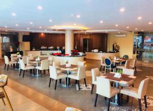 a restaurant with tables and chairs and a kitchen at Hotel MJ in Samarinda