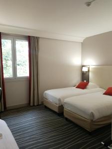 a hotel room with two beds and a window at Logis Hôtels- Hôtel et Restaurant Domaine de Fompeyre in Bazas