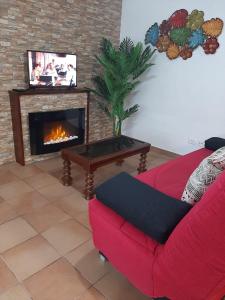 sala de estar con sofá rojo y chimenea en Casa La Torera, en Isora