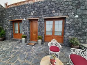 Casa de piedra con 2 sillas y mesa en Casa La Torera, en Isora