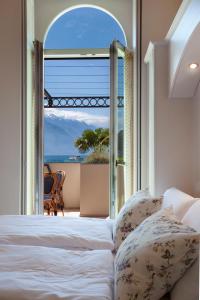 1 dormitorio con cama y vistas al océano en Bellavista Lakefront Hotel & Apartments en Riva del Garda
