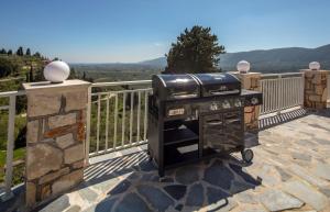 a grill on a patio with a fence and mountains at Demargia Villa in Áno Yerakaríon