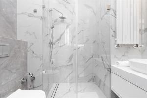 a white bathroom with a shower and a sink at Premium Apartments Business Center by Renters Prestige in Warsaw