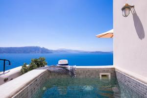 a hat sitting on the edge of a swimming pool at Pezoules of Oia in Oia +67 photos