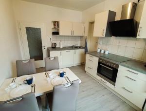 a kitchen with a table and chairs and a kitchen with white cabinets at Ferienwohnung am Lerchenberg in Dankmarshausen