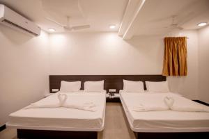 two beds in a room with white sheets at Gopuram Residency in Madurai