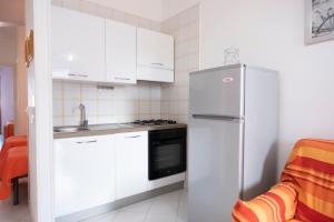 a kitchen with white cabinets and a refrigerator at Appartamento Sole in San Vito lo Capo