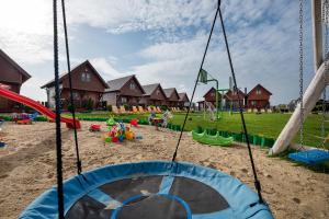 un parque infantil con columpios en la arena en Domki Magnati en Władysławowo