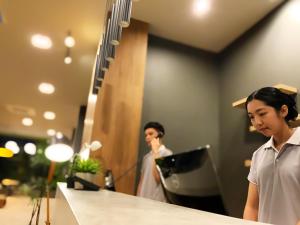 a woman standing in front of a mirror with a laptop at bliQ Hotel Chanthaburi in Chanthaburi