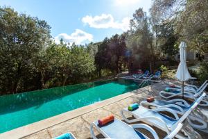 a swimming pool with lounge chairs and an umbrella at Villa Muscarolas By home villas 360 in Pollença