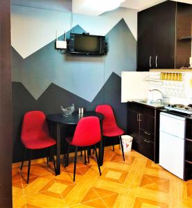 a kitchen with a black table and red chairs at Marco Polo, Mountain View Apartment in Gudauri