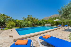 a swimming pool with two blue chairs and umbrellas at Casa de Campo con Encanto in Pollença