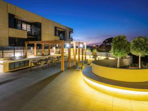 a rooftop patio with tables and chairs at night at The Sebel Melbourne Malvern in Melbourne