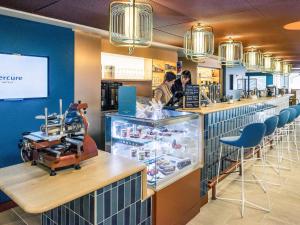 a restaurant with a counter with blue walls and chairs at Mercure Toulouse Centre Saint-Georges in Toulouse