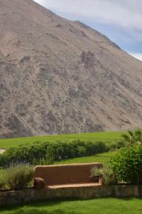 a bench in a field with a mountain in the background at Refugio Misterios del Elqui in Pisco Elqui