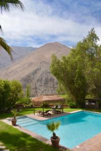 a swimming pool with a mountain in the background at Refugio Misterios del Elqui in Pisco Elqui