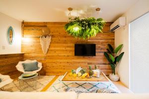 a living room with a wooden wall with a tv at Guesthouse Seawall in Ginowan