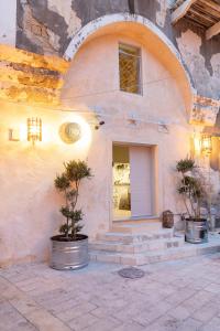 a building with a door and two trees in buckets at Melisende in ‘Akko