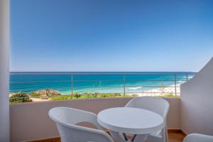 a white table and chairs on a balcony with the beach at Clube Porto Mos - Sunplace Hotels & Beach Resort in Lagos